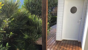 Una terraza de madera con una puerta blanca y una ventana pequeña.