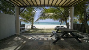 A covered outdoor area with a picnic table, benches, and a view of the beach and ocean. - Pointe D Esny: House / Villa - Pointe d''Esny (Pointe d'Esny)