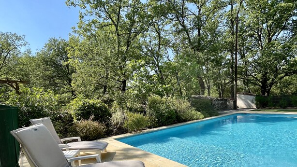 Una piscina con sillas de descanso y una pared de piedra.