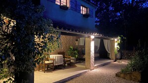Una casa de dos pisos con un patio cubierto, una mesa de comedor y sillas.