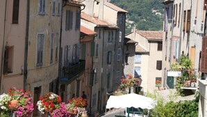 Una calle estrecha flanqueada por edificios, una mujer caminando y una montaña al fondo.