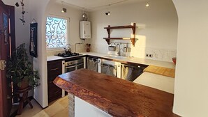 A kitchen with a wooden countertop, a built-in oven, a gas stove, and a window with a decorative view. - SEAFRONT APARTMENT (Tarifa)