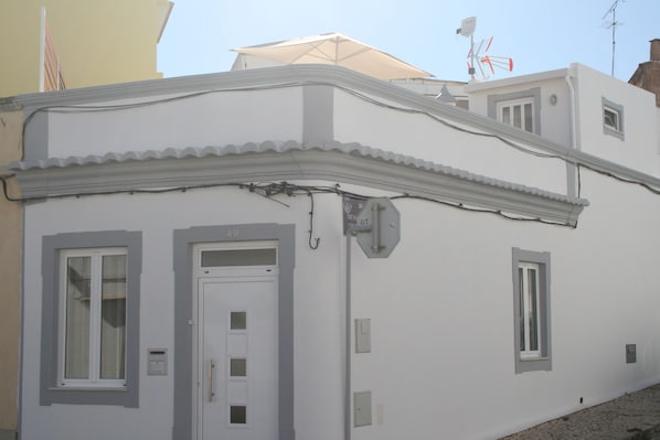 A building with a white facade, a door with a window, and a small window on the side.