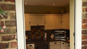 Une cuisine avec des meubles blancs, un four à micro-ondes et un mur en briques.