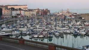 Un port de plaisance rempli de bateaux, un pont au premier plan et des bâtiments en arrière-plan.