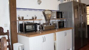 Une cuisine avec des meubles blancs, un plan de travail en bois, un four à micro-ondes, un grille-pain et un réfrigérateur.