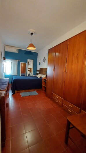 Un dormitorio con cama, armario y escritorio.