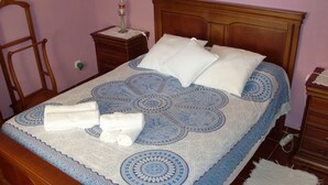 Un lit bien fait, avec une couvre-lit à motifs, des oreillers et des serviettes pliées.