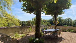 Un patio al aire libre con una mesa y sillas, rodeado de grava y follaje.