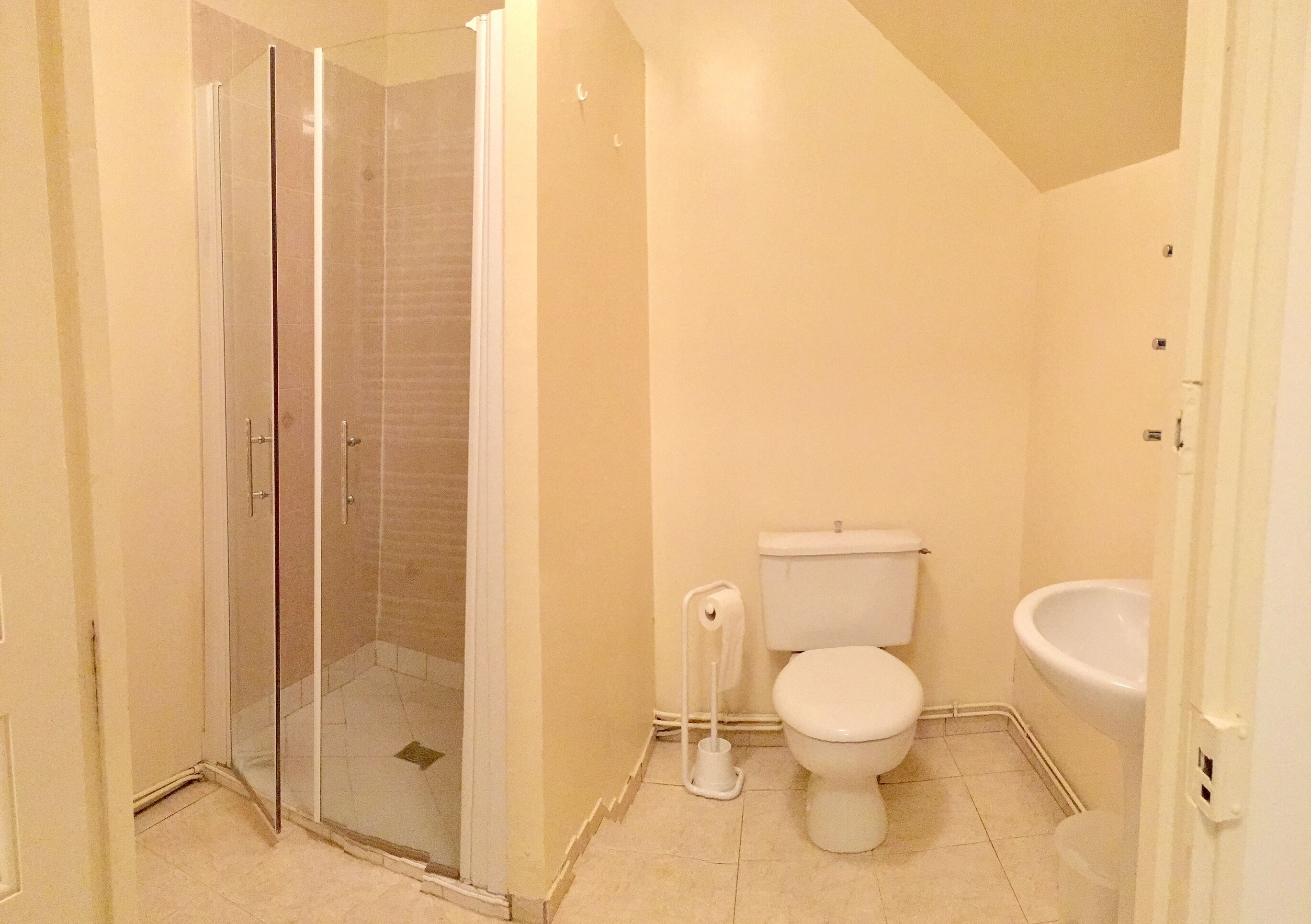 Une salle de bain avec une douche à parois de verre, des toilettes et un lavabo.