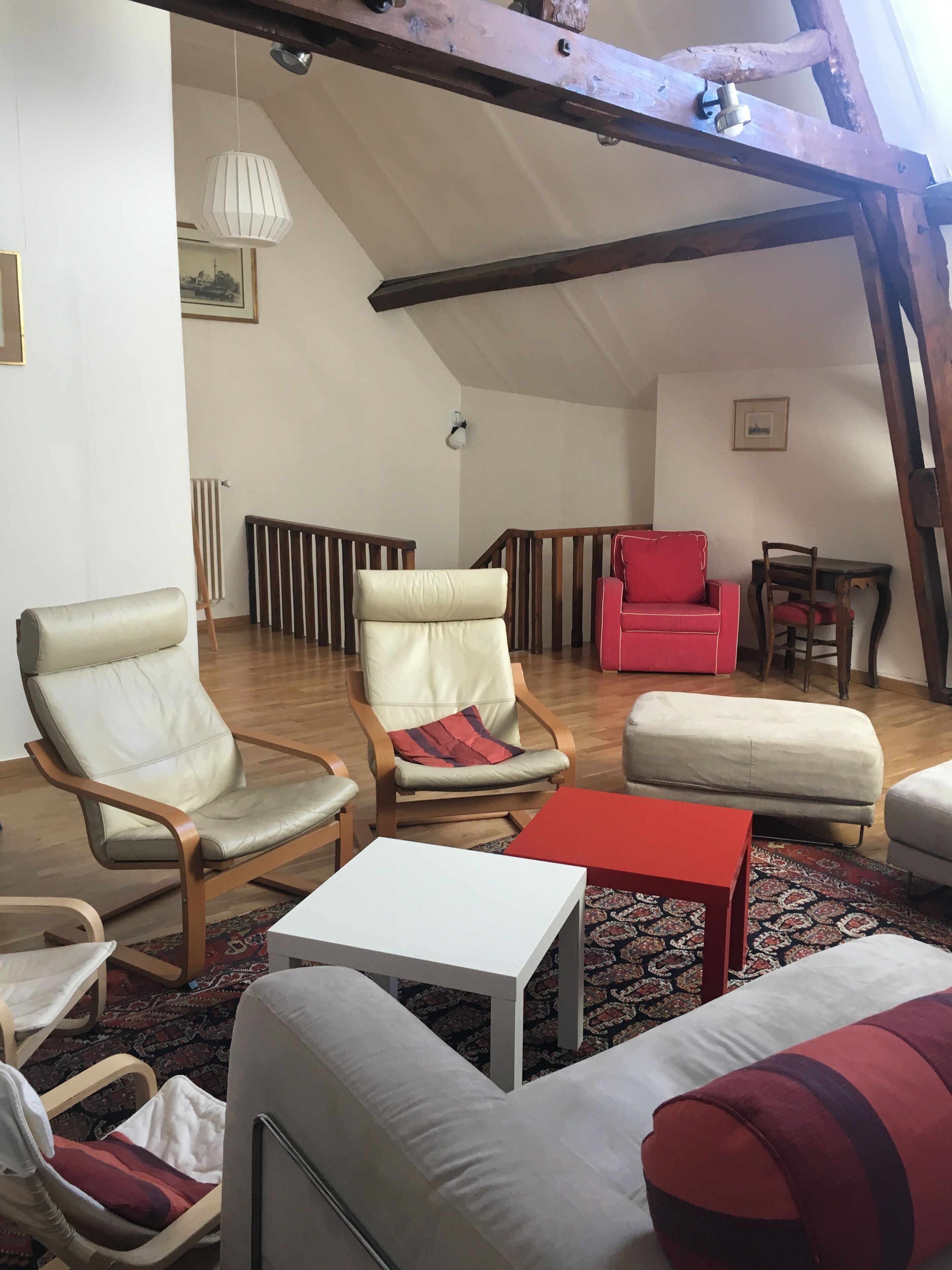 A loft-style living room with high ceilings, exposed beams, and a mix of modern and traditional furniture.