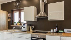 Une cuisine moderne équipée d’un four encastré, d’une machine à café et d’une fenêtre agrémentée de plantes.