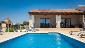 Une piscine avec des chaises longues et un espace patio couvert.