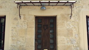 A stone building with a wooden door, two potted plants, and a metal awning above the door. - A charming stone house with unique views of the Dordogne River (Bergerac)