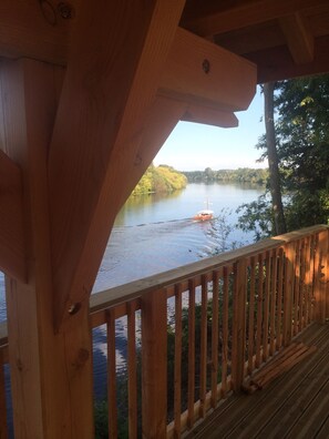 A wooden deck overlooking a calm river with a boat. - A charming stone house with unique views of the Dordogne River (Bergerac)