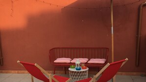 A patio with two red folding chairs, a small round table with a lantern, and a blue umbrella. - Large and quiet detached house in the historic center - CIN IT091095C2000S3477 (Tortolì)