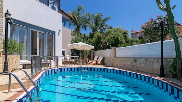 A swimming pool with blue tiles, a lounge area with chairs and a table, and a building with large windows and a stone wall. - Villa Kallergi - Nefeli (450 m2) House for 6, west-central Crete (Rethymnon)
