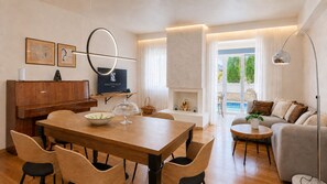 A modern living room with a dining area, a television, and a view of a pool.