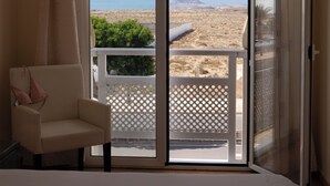 A hotel room with a bed, a chair, and a balcony with a view of a desert landscape. - Apartment with WIFI  in a beatiful complex (Corralejo)