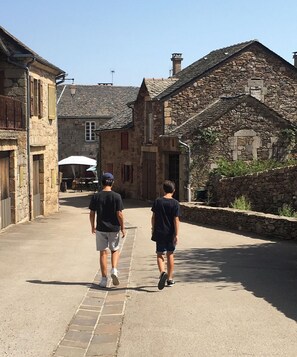 Dos personas caminando por una calle empedrada flanqueada por edificios de piedra.