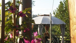 Ein Pavillon mit weißem Baldachin, umgeben von Grünpflanzen und Blumen.