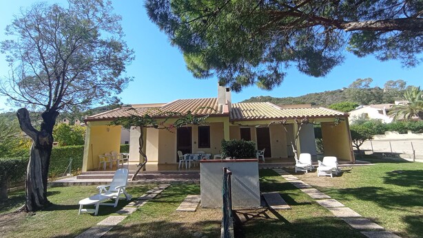 Ein Haus mit Ziegeldach, einer Veranda mit Sitzgelegenheiten und einem Rasen.