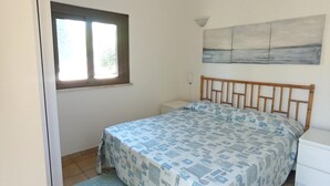 Ein Schlafzimmer mit Bett, Fenster, einem Bild und einem Nachttisch.