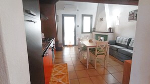 Eine Küche mit Herd und Backofen, ein Esstisch mit Stühlen und ein Sofa im Wohnbereich.
