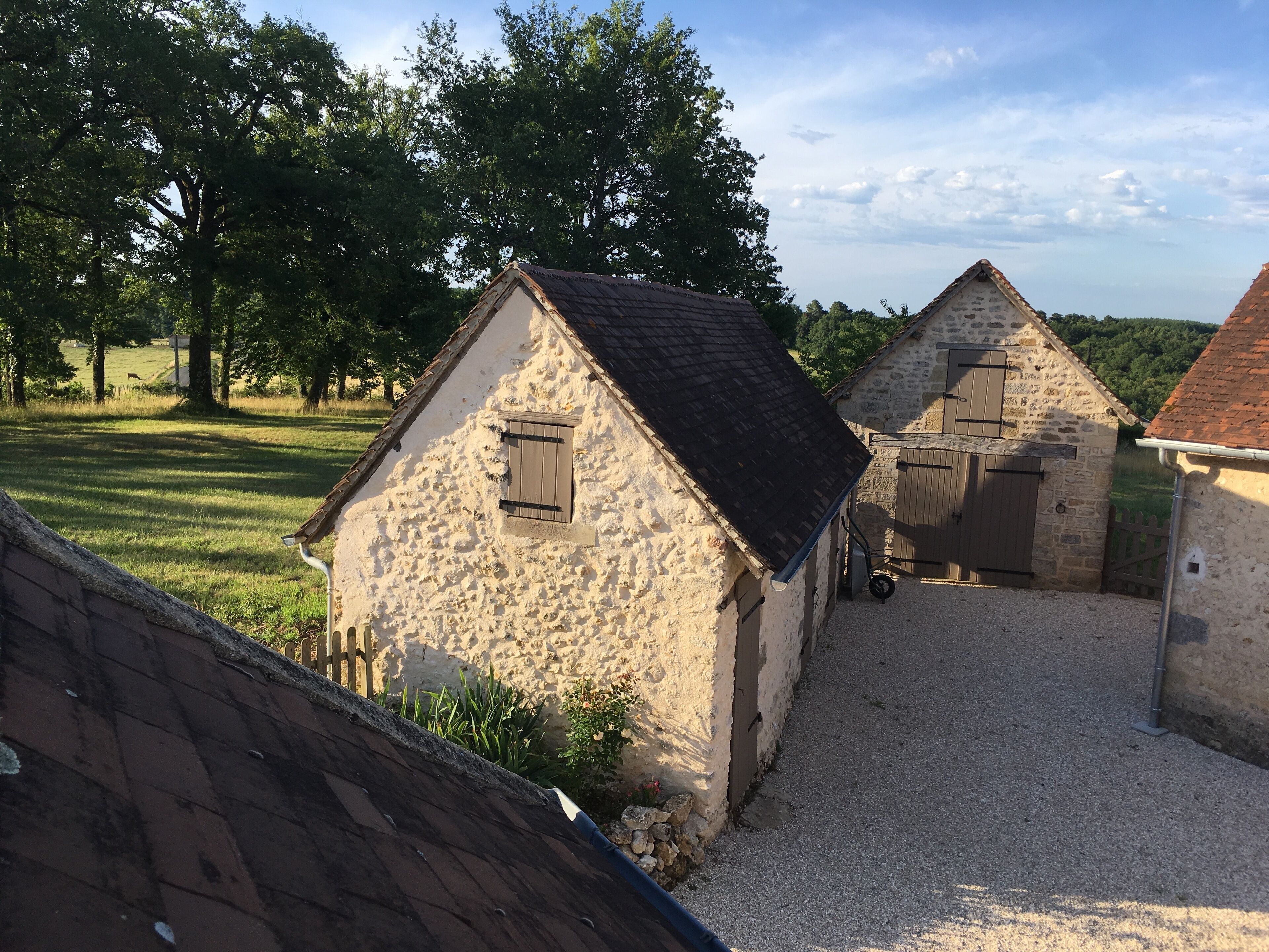 A rustic stone building with a gravel driveway and a wooden fence.