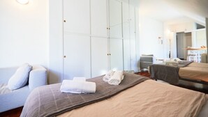 Une chambre d’hôtel avec un lit, un canapé, un miroir et une armoire.