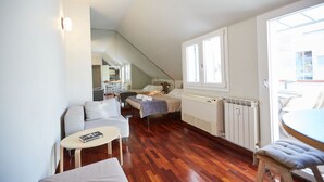 Un espace de vie compact comprenant un canapé, une petite table, un lit et un coin repas.