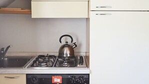 Une cuisine équipée d’une cuisinière à gaz, d’une bouilloire et d’un évier.