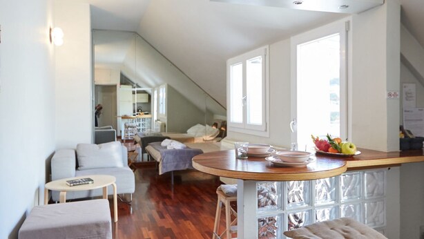 Une cuisine moderne avec un plan de travail en bois, un coin repas avec un canapé et un escalier menant à un autre niveau.