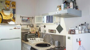 Eine kompakte Küche mit Kühlschrank, Mikrowelle, Spüle und einem kleinen Backofen. Es befinden sich verschiedene Küchenutensilien und Geräte vorhanden, darunter eine Kaffeemaschine und ein Wasserkocher.