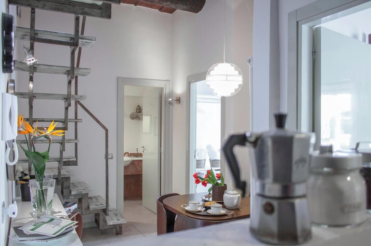 Une cuisine moderne équipée d’une machine à café, d’une table à manger agrémentée d’un vase de fleurs et d’un escalier avec une échelle.