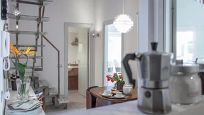 Eine moderne Küche mit einer Kaffeemaschine, einem Esstisch mit Blumenvase und einer Treppe mit Leiter.