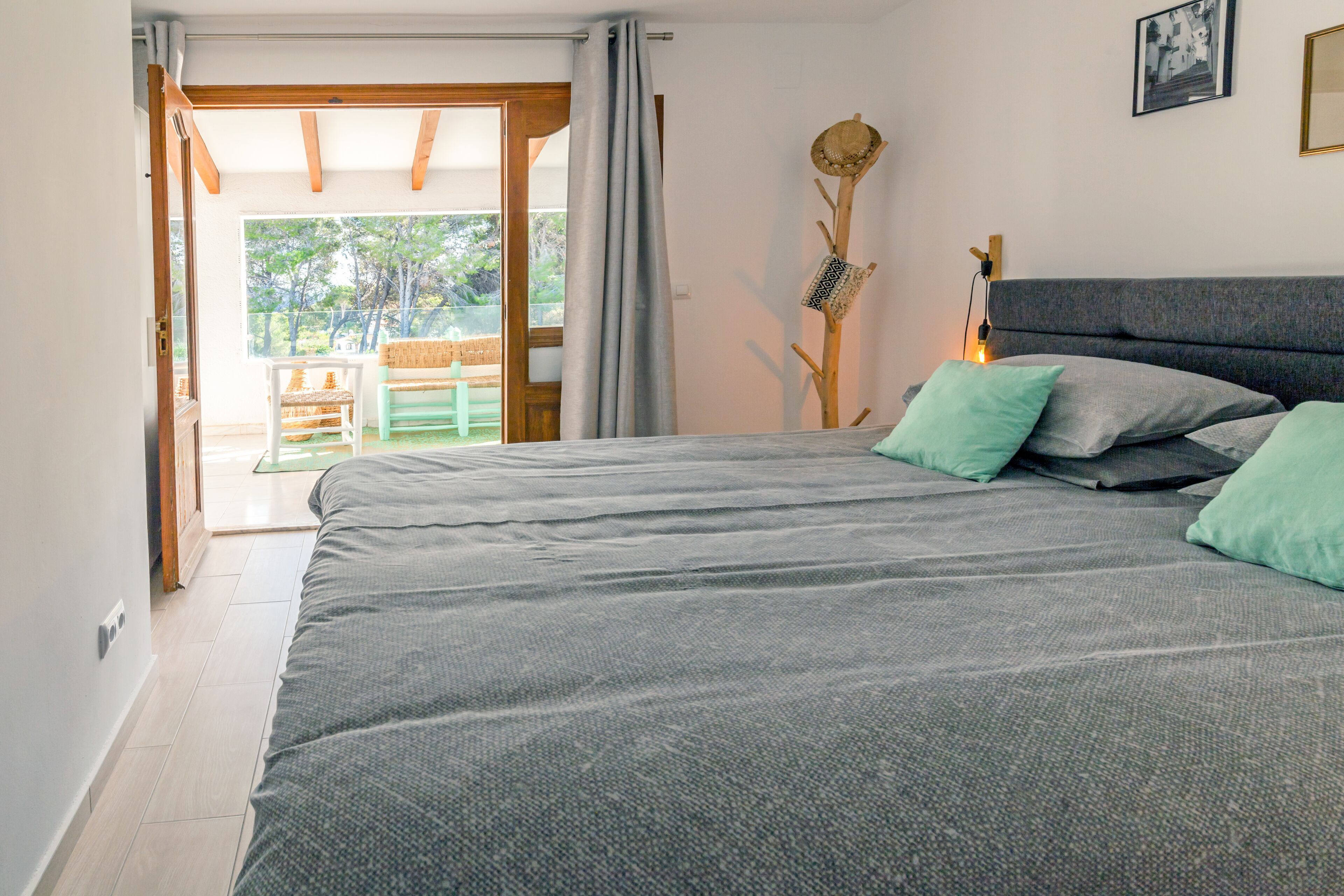 A bedroom with a large bed, a wooden headboard, and a view of the outdoors through an open door.
