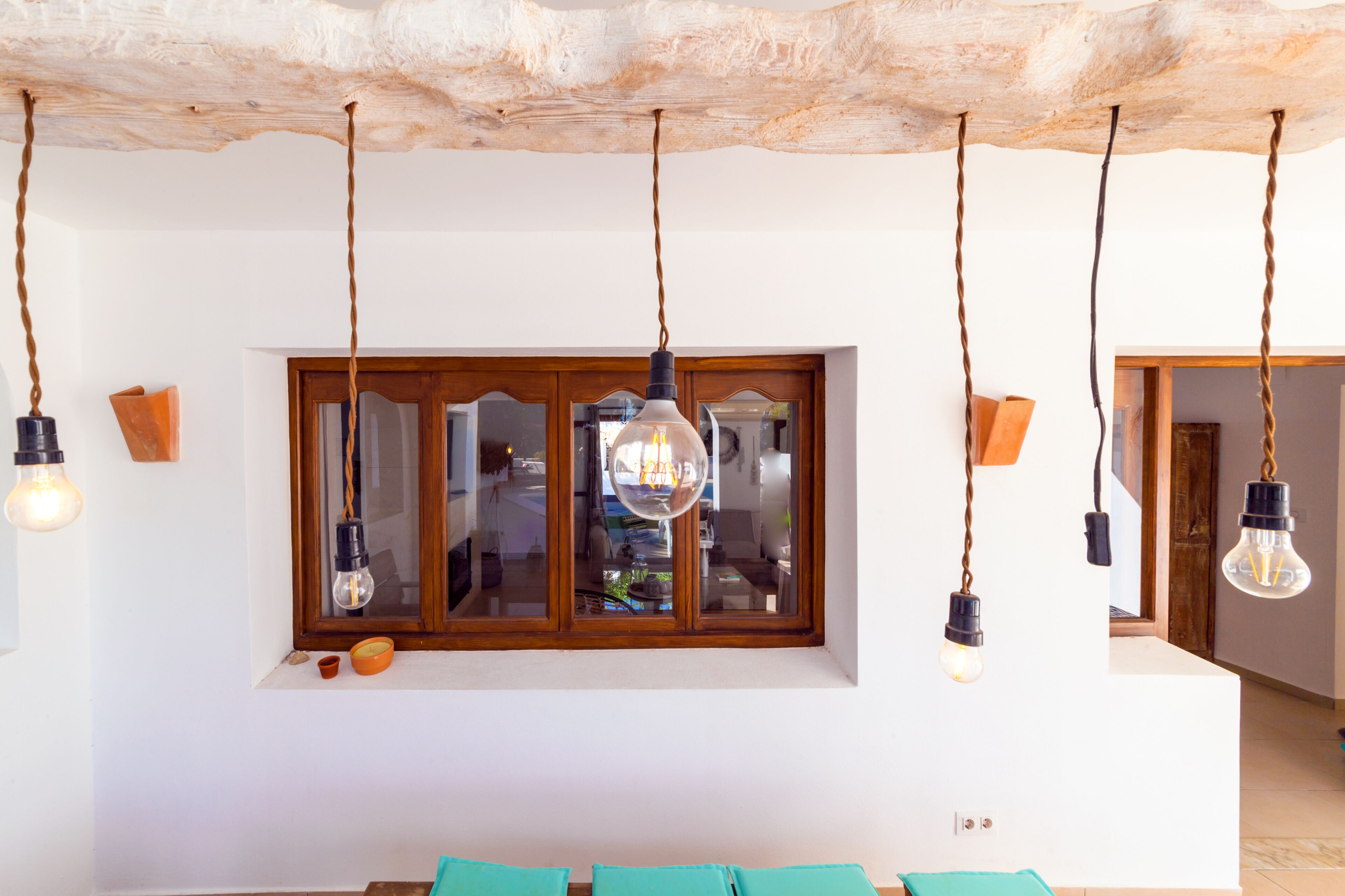 A room with a rustic ceiling, a large window with a view, and hanging pendant lights.