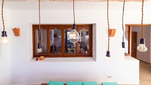 Una stanza con travi a vista rustiche, un'ampia finestra con vista e lampade pendenti.