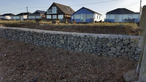 A coastal residential area with houses, a stone retaining wall, and a gravel path. - Beach Retreat - the perfect seaside escape. (Seasalter)