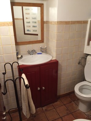 A bathroom with a white sink, red cabinets, a mirror, and a toilet. - Charming house inside walls of Óbidos (Óbidos)