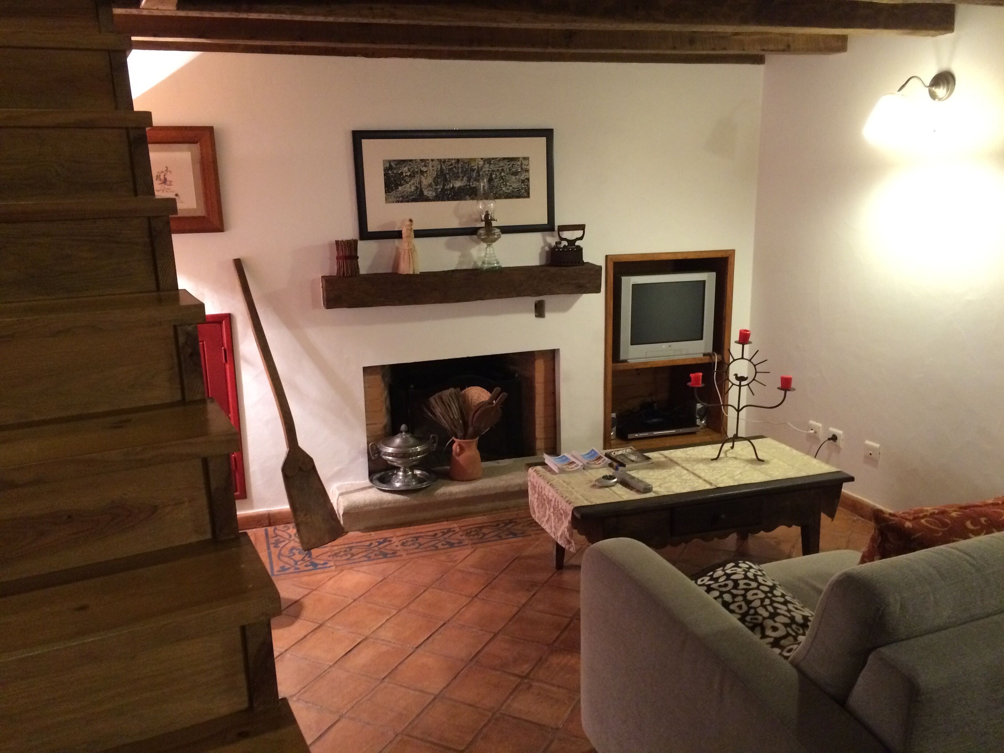 Un salon chaleureux avec une cheminée, un téléviseur et une table sur laquelle sont posés des livres et une bougie.