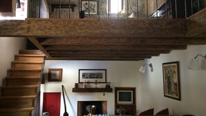Un intérieur rustique avec un escalier en bois, une cheminée, un canapé et un téléviseur.