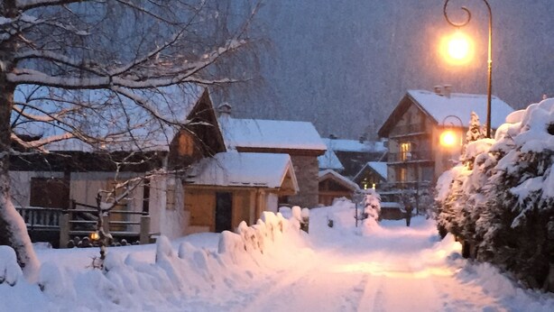 Un pueblo cubierto de nieve con edificios de madera y un farol.