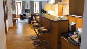 Una cocina moderna con una isla central, taburetes de bar y un área de comedor al fondo.
