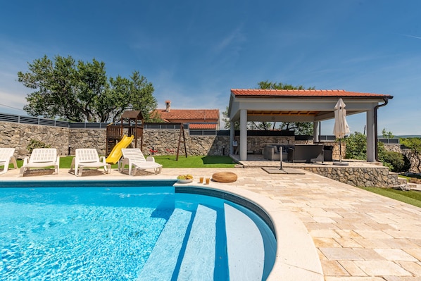 A swimming pool with lounge chairs, a slide, and a covered patio area. - Villa Elder ZadarVillas (Lepuri)