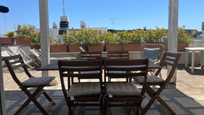 Eine Terrasse im Freien mit Holzmöbeln, einem Tisch und Topfpflanzen.