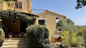 A rustic building with a stone facade, a wooden staircase leading to a porch, and a garden with various plants and flowers. - Villa With Pool In St Paul En Foret, Nr Fayence, Cote D'azur-Provence, France (Saint-Paul-En-Forêt)