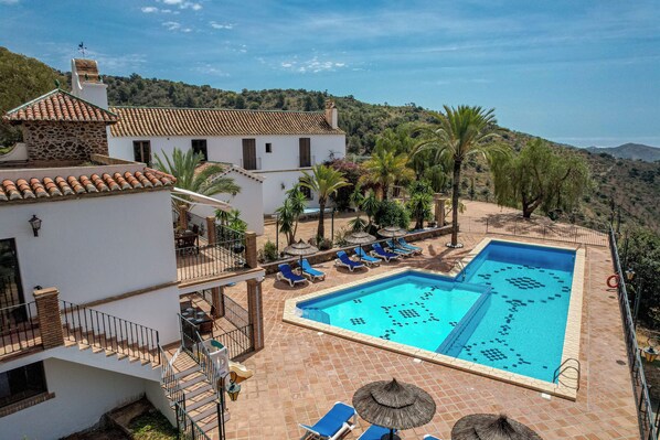 Zona de piscina con sillas reclinables azules y una vista despejada del paisaje circundante.