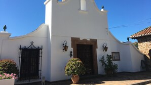 A white building with a curved facade, a wooden door, and two black wrought iron gates. - Jasmine Padre Aviles 17th C converted convent with pool, tennis & amazing views (Malaga)